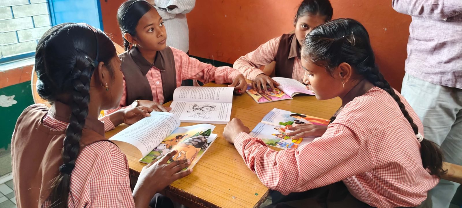 Students reading storybooks together around a table